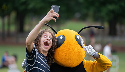 A Georgia Tech student poses with Buzz, Tech’s yellow jacket mascot.